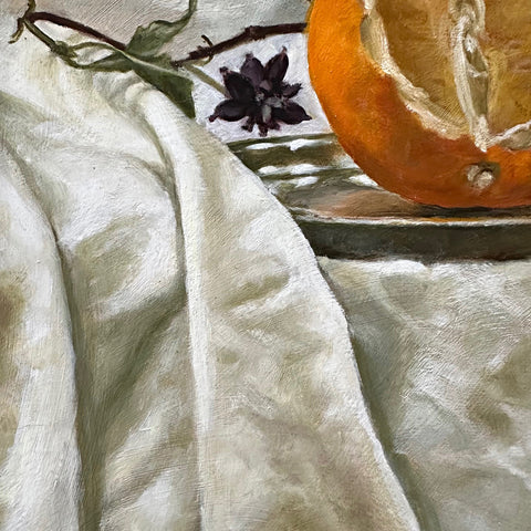 Detail of a still life oil painting of a cut orange on a silver plate against a dark green background with vines on a white tablecloth by Davette Leonard at Cottage Curator - Sperryville VA Art Gallery