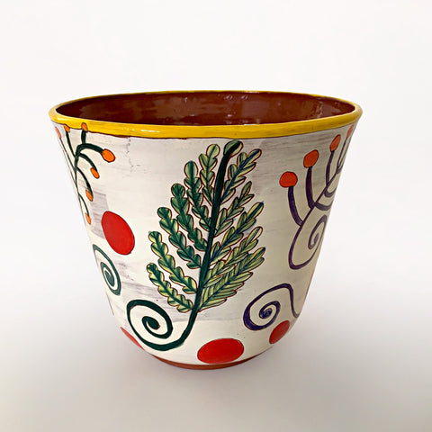Ceramic vessel with clay red interior and white exterior decorated with bold green, blue, purple and orange plant leaves, with red dots surrounding and a yellow rim, by artist Sara Schneidman at Cottage Curator - Sperryville VA Art Gallery