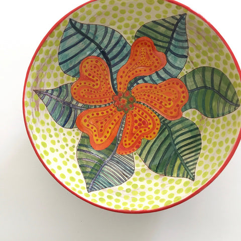 Top view of a round ceramic bowl with patterned orange and green flower and green polka dots by Sara Schneidman at Cottage Curator, Sperryville VA Art Gallery