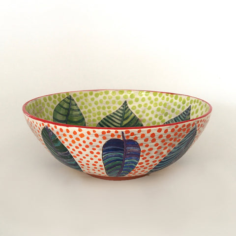 Side view of a round ceramic bowl with patterned blue and green leaves with red polka dots on the outside and green polka dots on the inside by Sara Schneidman at Cottage Curator, Sperryville VA Art Gallery